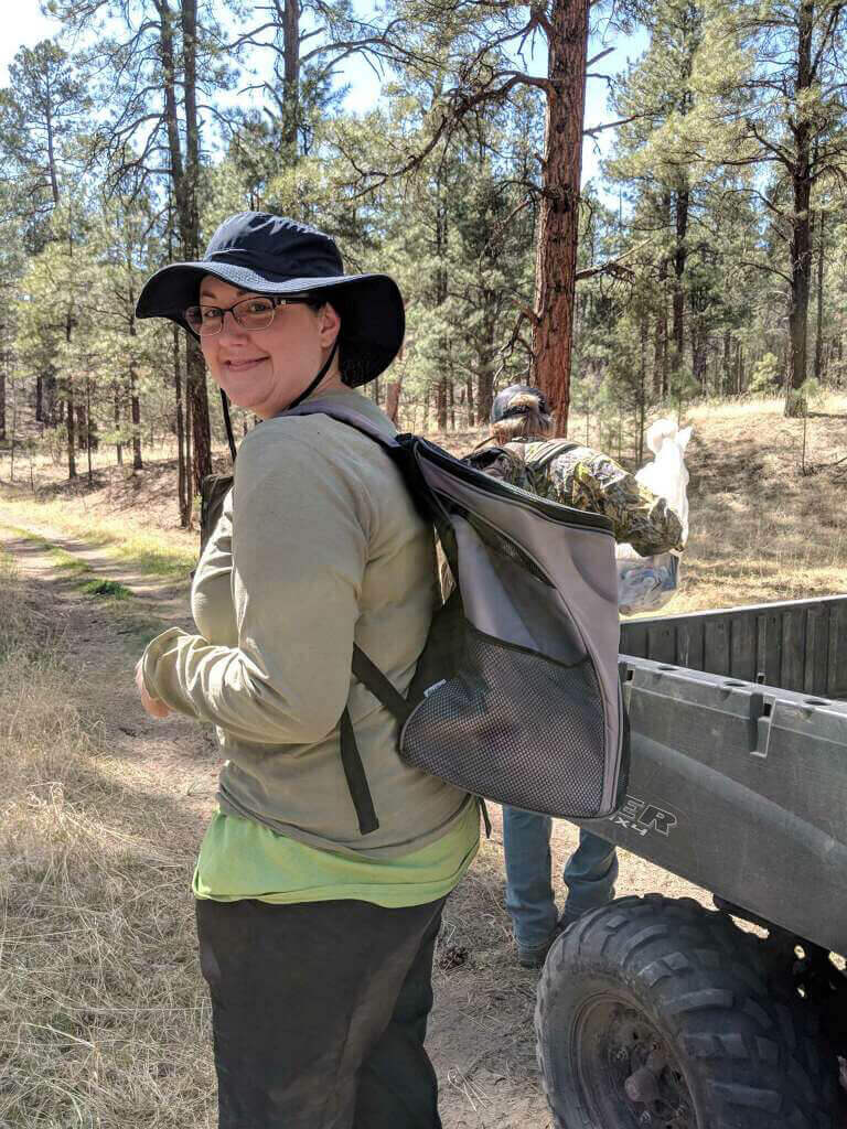 Endangered Wolf Center team with pups on their back ready to hike to wild den in New Mexico